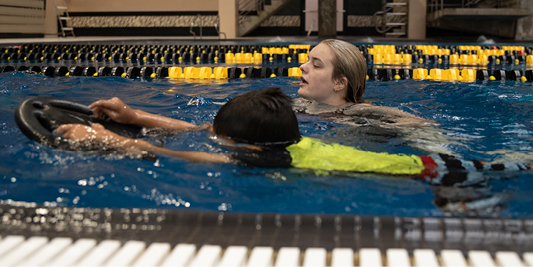 Student working as a swim instructor.